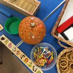 Pre-school children using wooden pegs to hammer into a pumpkin