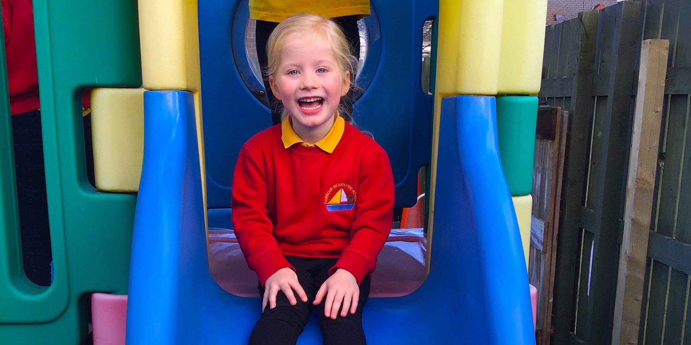 A pre-school child playing on an outdoor climbing frame