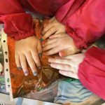 Pre-school children pressing down on paint during messy play
