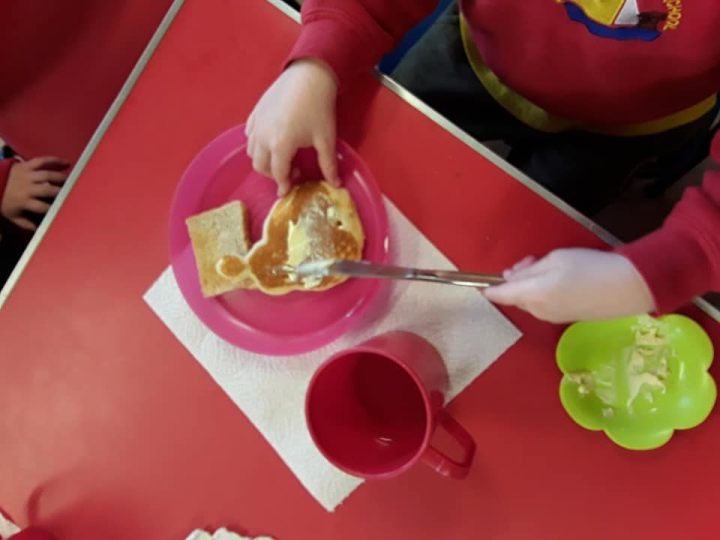 A pre-school child spreading butter onto a pancake