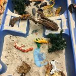 A variety of animal toys in the sand pit