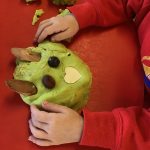 A pre-school child holding their play dough monster