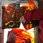 Pre-school children drawing pictures in paint pouches over a light box