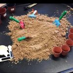 Pre-school children playing with sand and plant pots