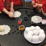 Pre-school children using coloured water to decorate cotton balls