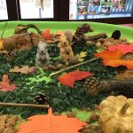 An Autumn scene with pinecones, leaves and play squirrels and pumpkins