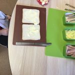 A child at a table with buttered bread and various fillings