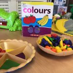 Fruit bowls with an assortment of play fruit and a book about colours