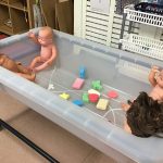 A water tray filled with dolls and sponges