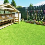 A view of the garden at Harbour Bears in the summer featuring a mud kitchen and flowers