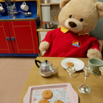 A table set with a tray of play-biscuits, a tea pot and cups
